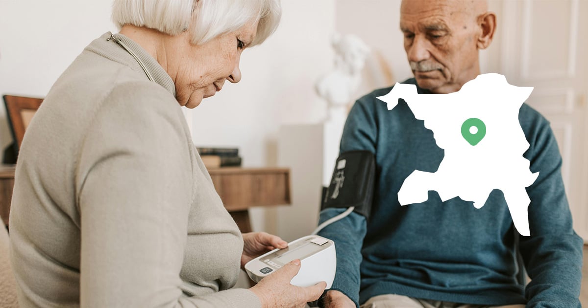 Einem älteren Mann wird zuhause geholfen seinen Blutdruck zu messen